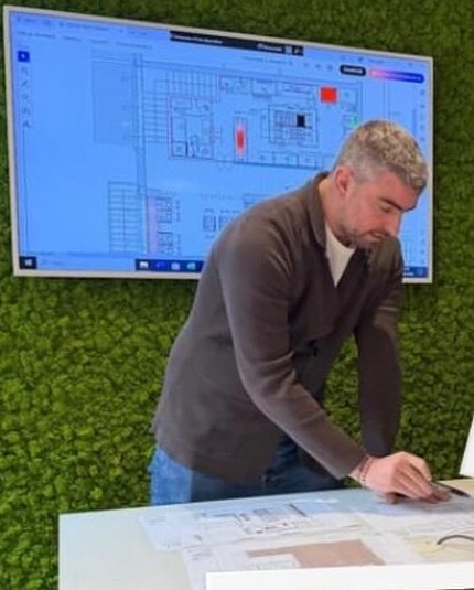 Filippo Fava chino sul tavolo mentre consulta le tavole di un progetto