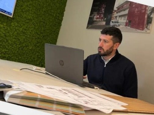 Matteo Sabattini al computer portatile, con le tavole di progetto sulla scrivania