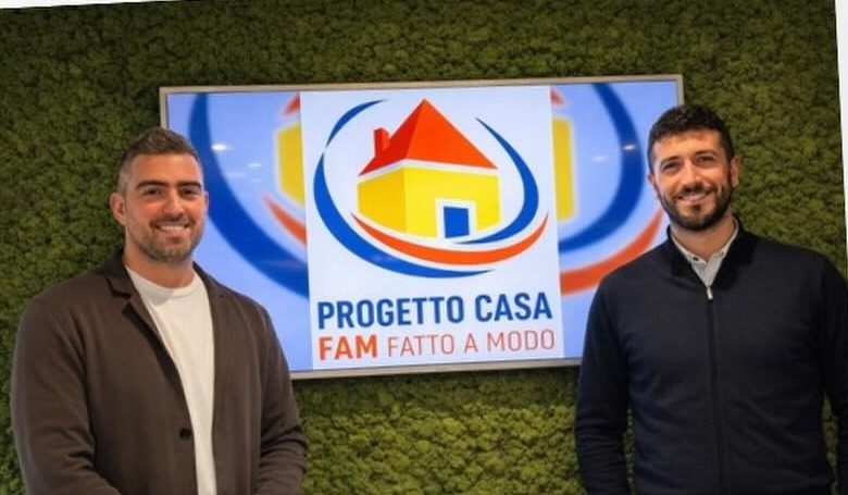 Filippo Fava e Matteo Sabattini sorridenti nel loro ufficio, davanti a uno schermo con il logo Progetto Casa FAM